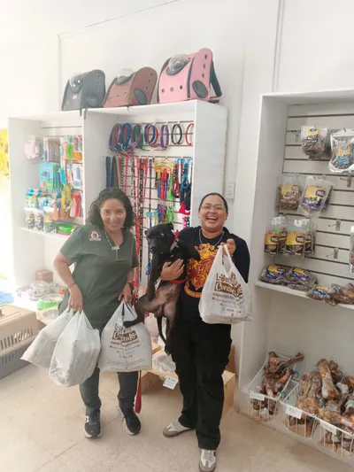 Clientes con perro negro y bolsas de compras en tienda Lomito Consentido, promoción de alimento natural para mascotas en Nicaragua.