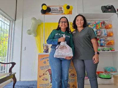Clientes en tienda con bolsa frente a stand Lomito Consentido, promoción de alimentos naturales para perros en Nicaragua.