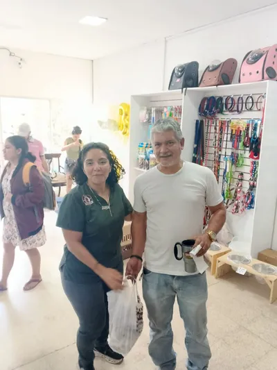 Clientes en tienda Lomito Consentido con bolsas de compras y decoración de aniversario, promoción de alimentos naturales para mascotas en Nicaragua.