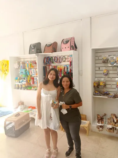 Clientes en tienda Lomito Consentido con bolsas de compras y estantes llenos de productos naturales para mascotas en Nicaragua.