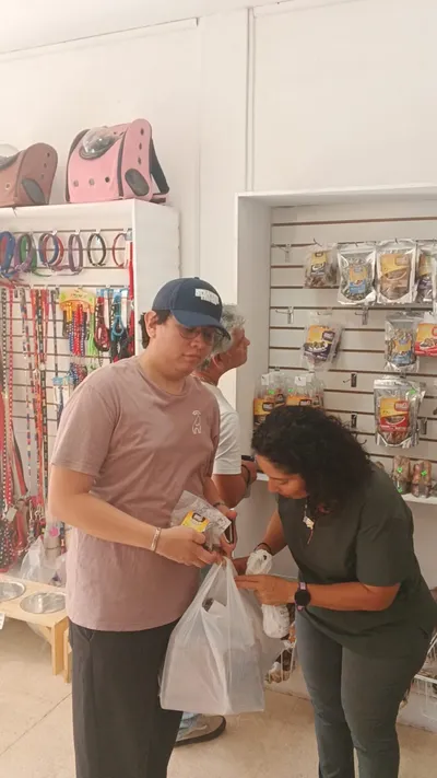 Clientes interactuando en tienda Lomito Consentido con bolsas y productos naturales para mascotas en Nicaragua.