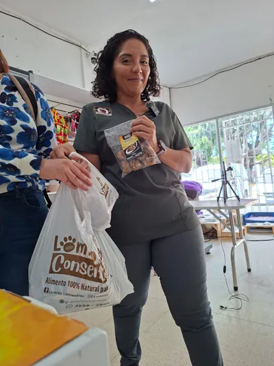 Representante en tienda mostrando paquete y bolsa de productos Lomito Consentido, promoción de alimentos naturales para mascotas en Nicaragua.