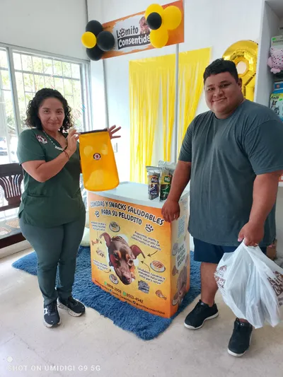 Stand promocional de Lomito Consentido con clientes mostrando bolsas y mesa decorada con snacks naturales para perros en Nicaragua.