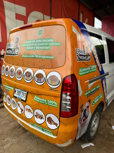 Van blanca y naranja con branding completo de Lomito Consentido, alimento natural para perros elaborado en Nicaragua.