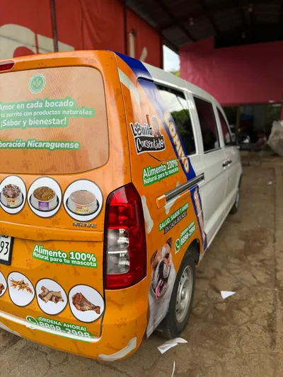 Van blanca y naranja Lomito Consentido con imágenes de productos naturales para perros elaborados en Nicaragua.